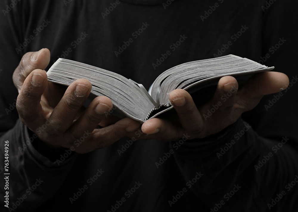 man praying to god with hands together on dark background stock photo